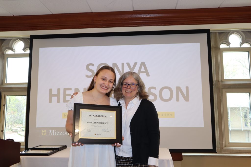 Sonya Hendrickson holding certificate at awards ceremony with Dr. Monnier.